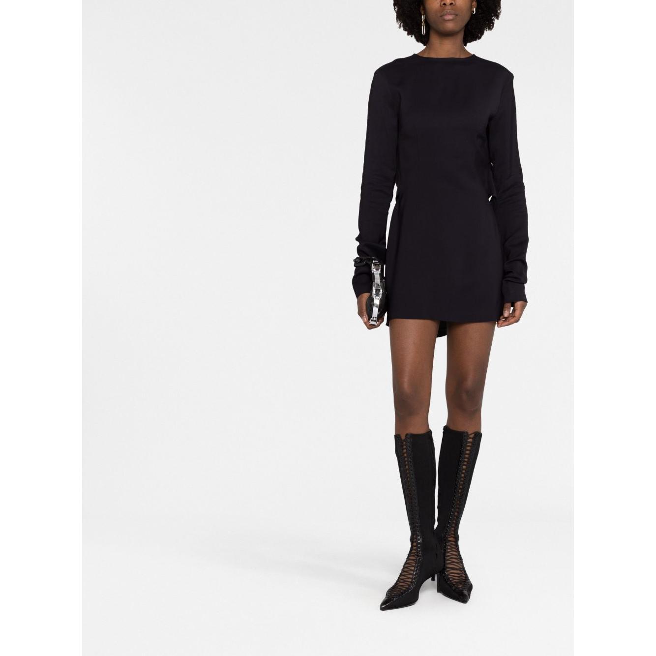 Model wearing black 032C 'Kicked Back' structured short dress with long sleeves and cut-out detailing, standing against a white background.