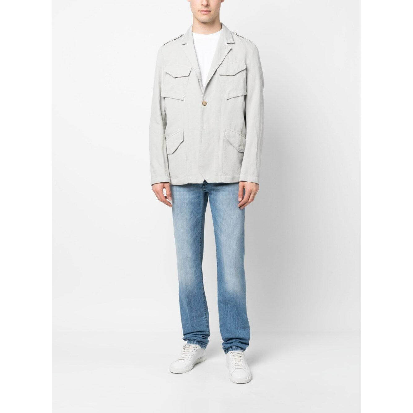 Man wearing Boglioli white single-breasted jacket with pocket detail, cotton-linen blend, paired with jeans and white sneakers.