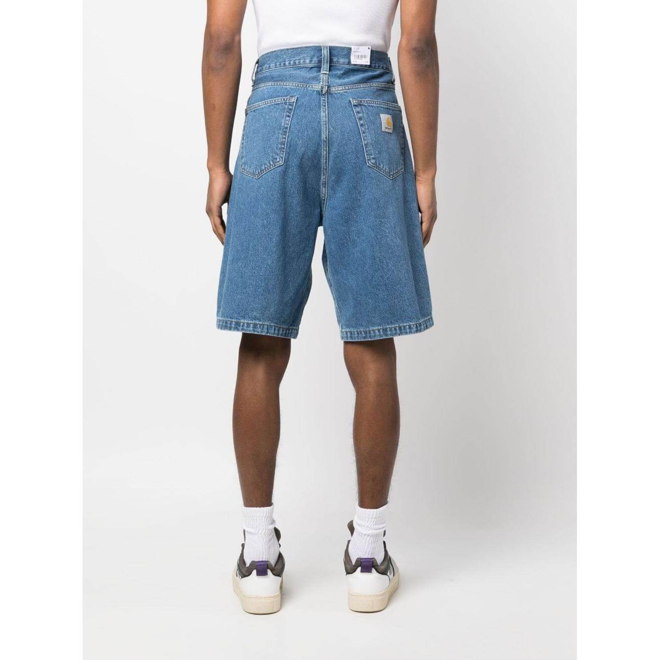 Back view of model wearing Carhartt WIP Main blue denim shorts with logo patch, knee-length fit, and classic five-pocket style.