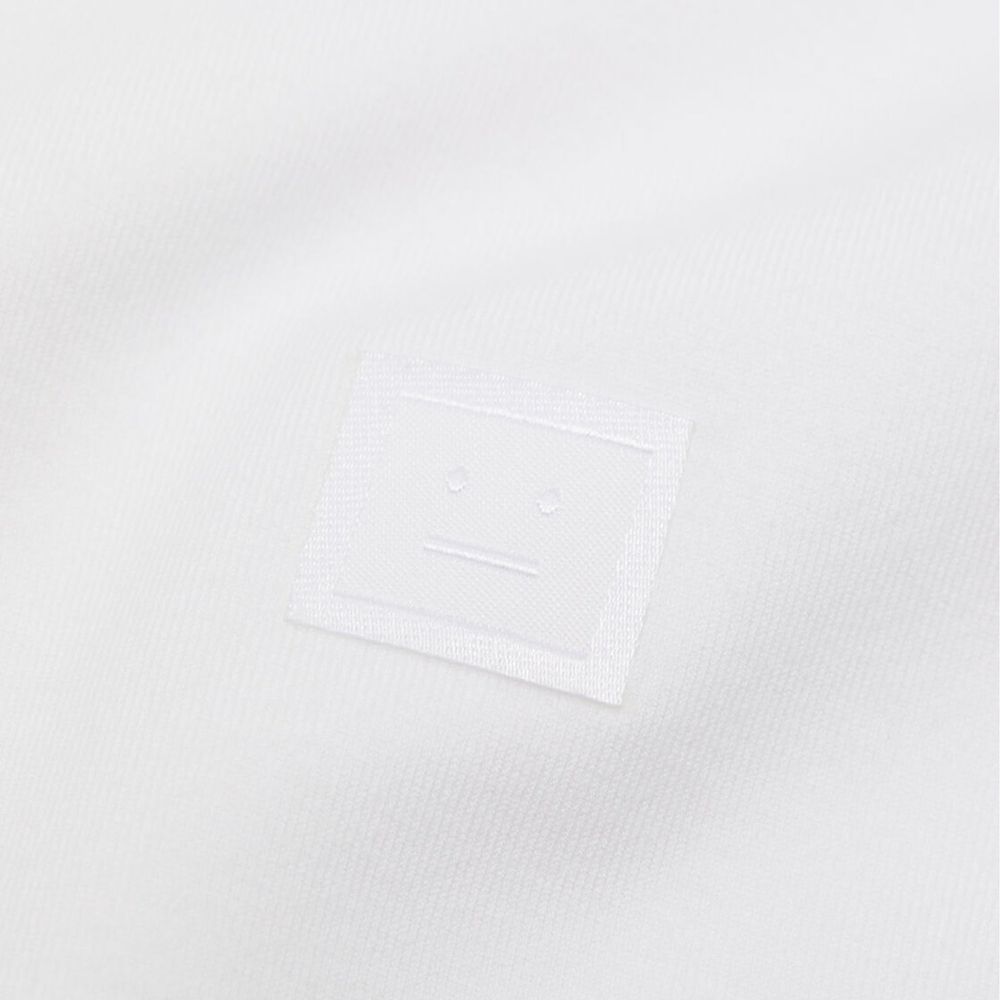 Close-up of face logo on Acne Studios White Cotton T-Shirt, 90% cotton, 10% elastane, unisex fit, made in Portugal.