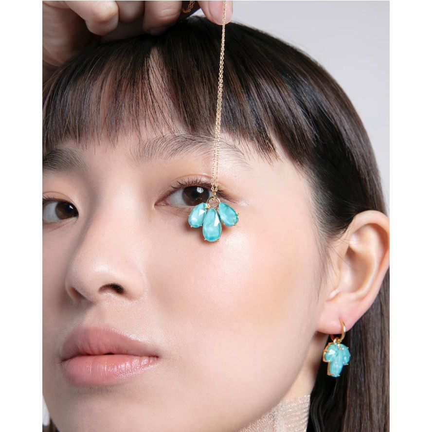 Woman wearing turquoise gemstone earrings and necklace with dangling design