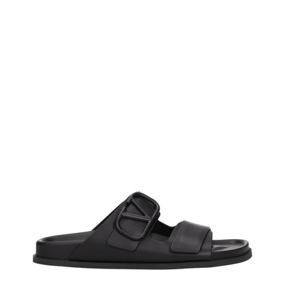 Valentino Garavani Black Leather Slippers with open toe and rubber sole, featuring a front logo design and low flat heel.