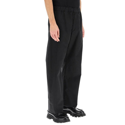 Alt Tag: Man wearing Alexander McQueen Black Cotton Casual Pants with elastic waist and pockets, side view.