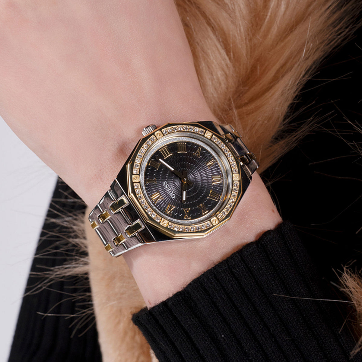 Person wearing GUESS WATCHES Mod. GW0770L4 with gold accents and a stylish black face.