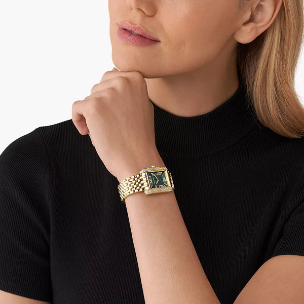 Woman wearing MICHAEL KORS Mod. EMERY wristwatch with gold strap and black dial, showcasing elegant style and design.