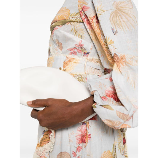 Zimmermann Ascension Ruffled Midi Dress with floral print and lace trim in light blue, wrap design with self-tie fastening, model holding clutch.